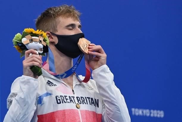 Bronze medallist Britain's Jack Laugher kisses his medal through his face mask after the men's 3m springboard diving final event during the Tokyo...