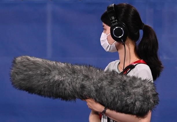 Journalist holds a microphone during the men's semi-final match of the Tokyo 2020 Olympic Games field hockey competition between Australia and...