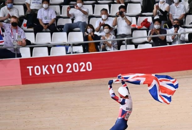 Britain's Matthew Walls holds a flag as he celebrates after winning the men's track cycling omnium points race during the Tokyo 2020 Olympic Games at...