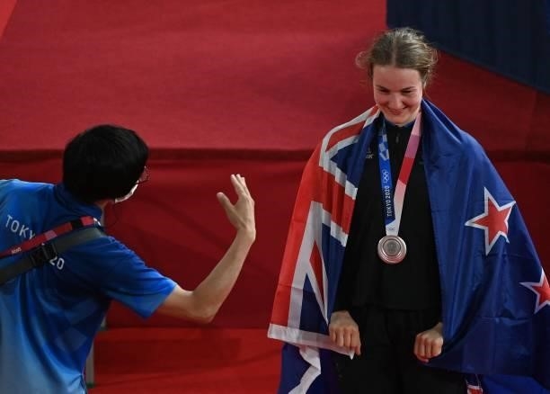 Tokyo 2020 official gestures to Silver medallist New Zealand's Ellesse Andrews as she poses for photographers with a flag and her medal after the...