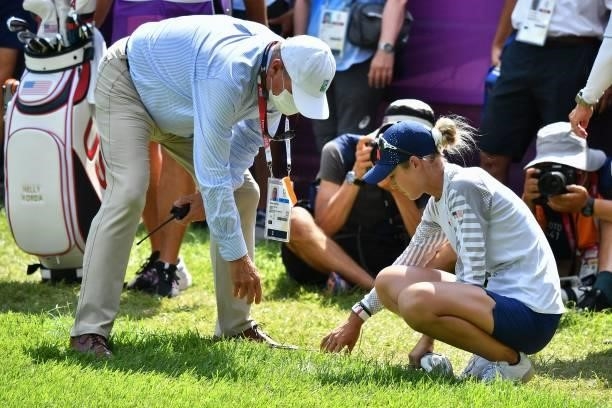 S Nelly Korda moves a cable that was near her ball as a match official looks on in round 3 of the womens golf individual stroke play during the Tokyo...