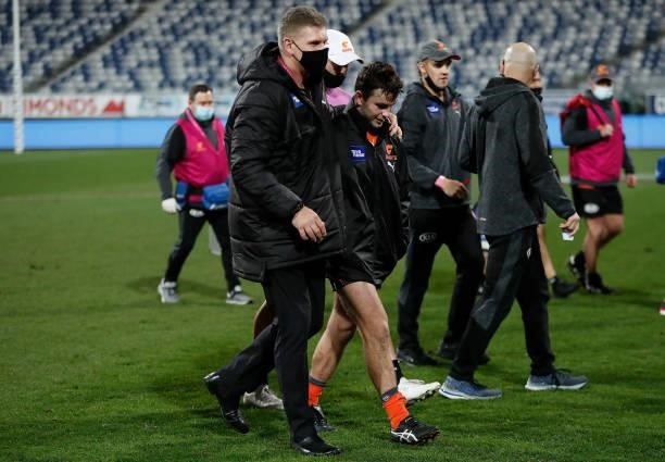 Brent Daniels of the Giants is consoled by Jason McCartney after injuring his hamstring during the 2021 AFL Round 21 match between the Geelong Cats...