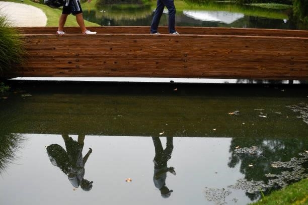 Justin Thomas and his caddie are reflected in the water at the 11th hole during the second round of the World Golf Championships-FedEx St. Jude...