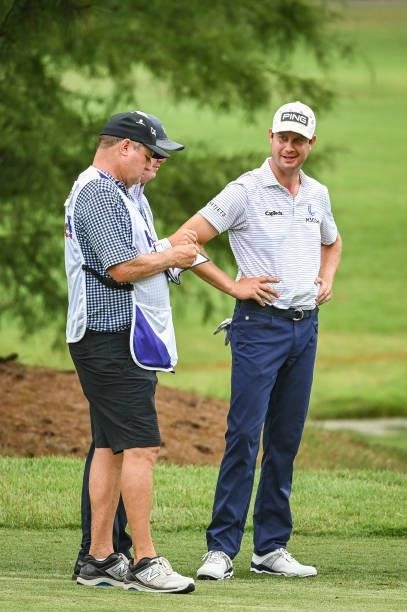Harris English smiles while talking to a rules official and his caddie on the ninth hole during the second round of the World Golf...