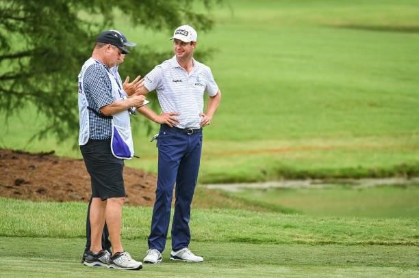 Harris English smiles while talking to a rules official and his caddie on the ninth hole during the second round of the World Golf...