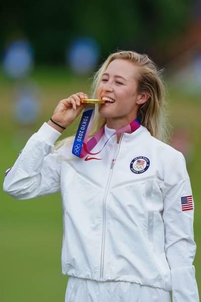 Gold medallist USA's Nelly Korda bites her medal on the podium during the victory ceremony of the womens golf individual stroke play during the Tokyo...