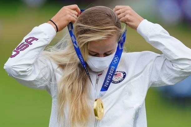 Gold medallist USA's Nelly Korda puts on her medal on the podium during the victory ceremony of the womens golf individual stroke play during the...