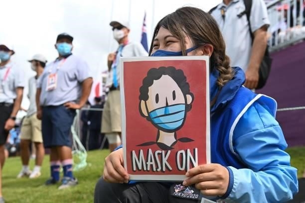 Volunteer holds a sign to indicate that players on the podium should put their masks back on during the victory ceremony of the womens golf...