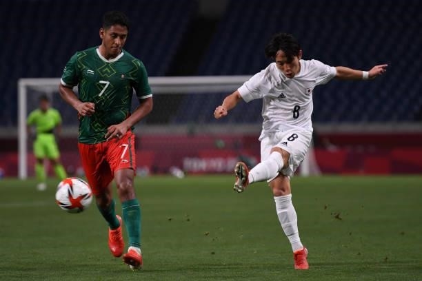 Koji Miyoshi of Japan shoots the ball under the pressure from Luis Romo of Mexico during the 3rd place match of the Men's Football between Mexico and...