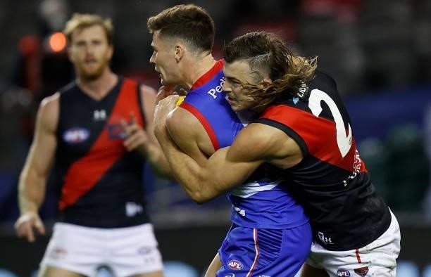 Josh Dunkley of the Bulldogs is tackled by Sam Draper of the Bombers during the 2021 AFL Round 21 match between the Western Bulldogs and the Essendon...