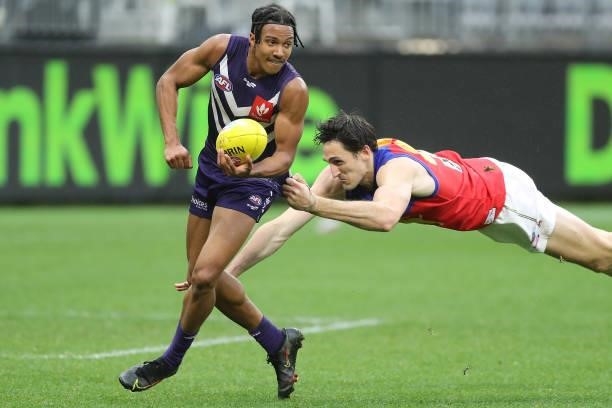 Brandon Walker of the Dockers handpasses the ball under pressure from Oscar McInerney of the Lions during the 2021 AFL Round 21 match between the...