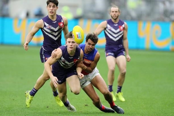 Caleb Serong of the Dockers is tackled by Callum Ah Chee of the Lions during the 2021 AFL Round 21 match between the Fremantle Dockers and the...