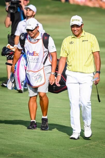 Hideki Matsuyama of Japan smiles with his caddie Shota Hayafuji on the 18th hole during a playoff in the final round of the World Golf...