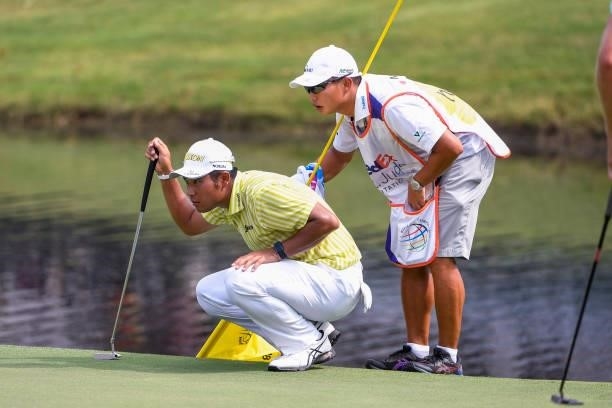 Hideki Matsuyama of Japan looks over his putt with his caddie at the 18th green during ta playoff in the final round of the World Golf...