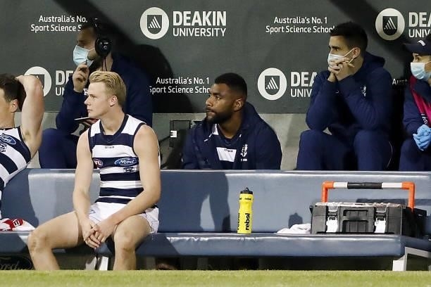 Esava Ratugolea of the Cats is seen sitting on the bench in his tracksuit after being substituted out of the game during the 2021 AFL Round 22 match...