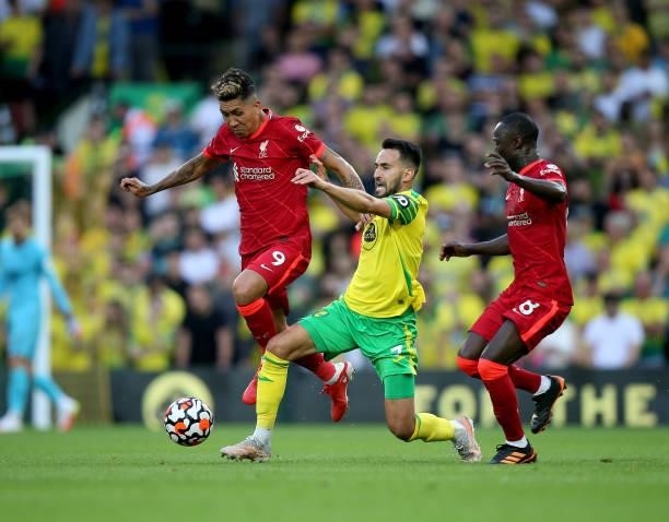 Lukas Rupp of Norwich City is challenged by Roberto Firmino and Naby Keita of Liverpool during the Premier League match between Norwich City and...