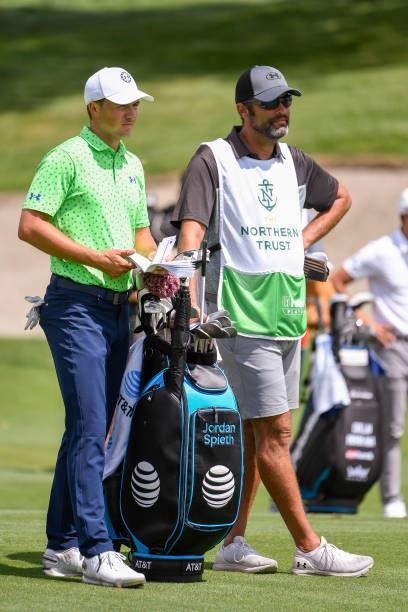 Jordan Spieth and caddie Michael Greller look over the yardage book at the eighth hole during the first round of THE NORTHERN TRUST at Liberty...