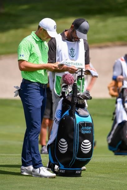 Jordan Spieth and caddie Michael Greller look over their yardage books at the eighth hole during the first round of THE NORTHERN TRUST at Liberty...