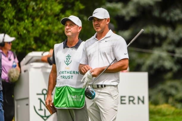 Brooks Koepka chats with his caddie at the ninth tee during the first round of THE NORTHERN TRUST at Liberty National Golf Club on August 19, 2021 in...