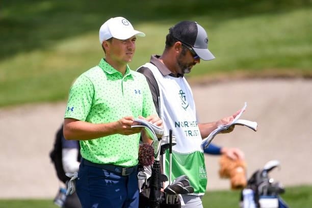 Jordan Spieth and caddie Michael Greller look over their yardage books at the eighth hole during the first round of THE NORTHERN TRUST at Liberty...