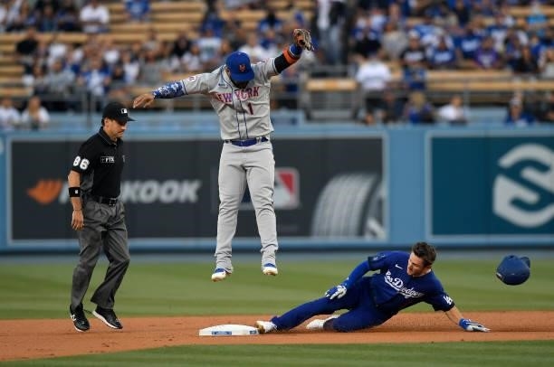 Jonathan Villar of the New York Mets leaps in the air for the high throw from right fielder Michael Conforto as Trea Turner of the Los Angeles...
