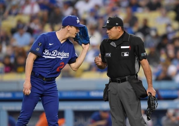 Pitcher Walker Buehler of the Los Angeles Dodgers talks with home plate umpire Nestor Ceja after hitting Michael Conforto of the New York Mets during...