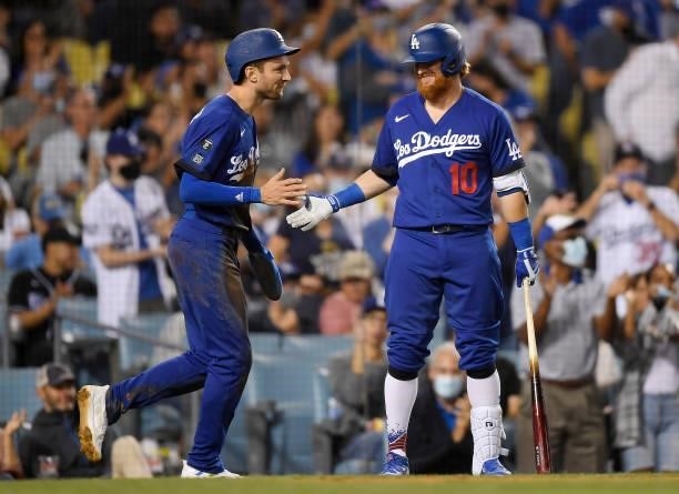 Trea Turner of the Los Angeles Dodgers is congratulated by Justin Turner after scoring a run on a double by Max Muncy during the third inning against...