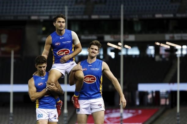 Jarrod Harbrow of the Suns is chaired off the ground by Sean Lemmens of the Suns and Zac Smith of the Suns after his final game during the 2021 AFL...