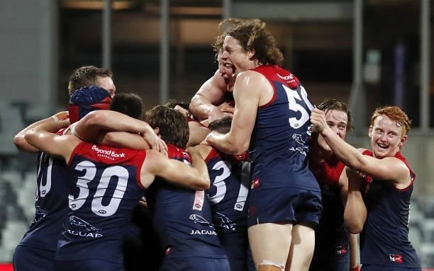 Melbourne players jump on Max Gawn of the Demons after kicking a goal after the final siren to win the match during the 2021 AFL Round 23 match...