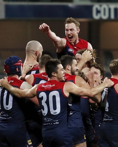 Harrison Petty of the Demons jumps on Max Gawn of the Demons after he kicks a goal to win the match after the final siren during the 2021 AFL Round...