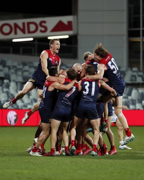 Melbourne players jump on Max Gawn of the Demons after kicking a goal after the final siren to win the match during the 2021 AFL Round 23 match...