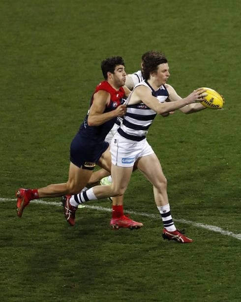 Max Holmes of the Cats is tackled by Christian Petracca of the Demons during the 2021 AFL Round 23 match between the Geelong Cats and the Melbourne...