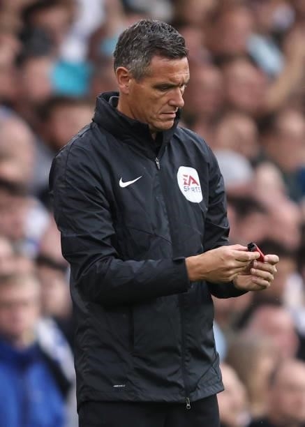Fourth official Andre Marriner examines an object handed to him by Referee Darren England during the Premier League match between Leeds United and...