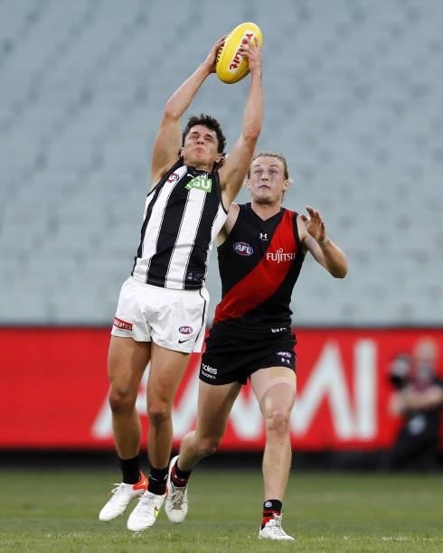 Trent Bianco of the Magpies marks the ball ahead of Mason Redman of the Bombers during the 2021 AFL Round 23 match between the Essendon Bombers and...