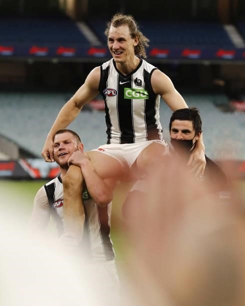 Chris Mayne of the Magpies is chaired off the ground by Taylor Adams of the Magpies and Scott Pendlebury of the Magpies during the 2021 AFL Round 23...