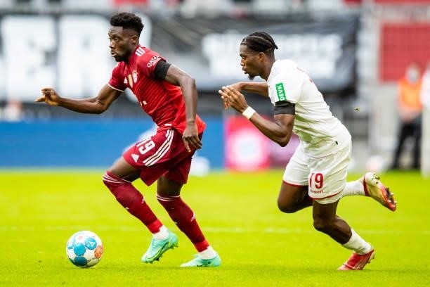 Alphonso Davies of Bayern Muenchen and Kingsley Ehizibue of 1. FC Koeln battle for the ball during the Bundesliga match between FC Bayern Muenchen...