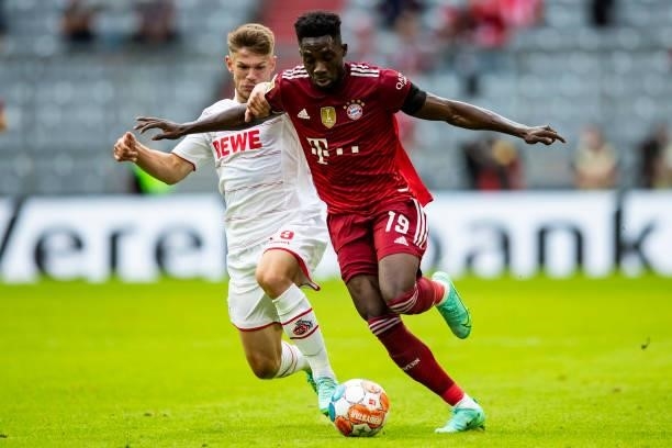 Jan Thielmann of 1. FC Koeln and Alphonso Davies of Bayern Muenchen battle for the ball during the Bundesliga match between FC Bayern Muenchen and 1....