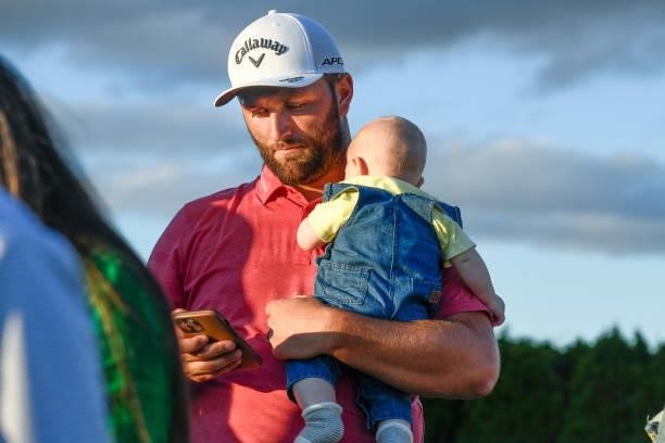 Jon Rahm of Spain holds his baby while watching the playoff during the weather delayed final round of THE NORTHERN TRUST at Liberty National Golf...