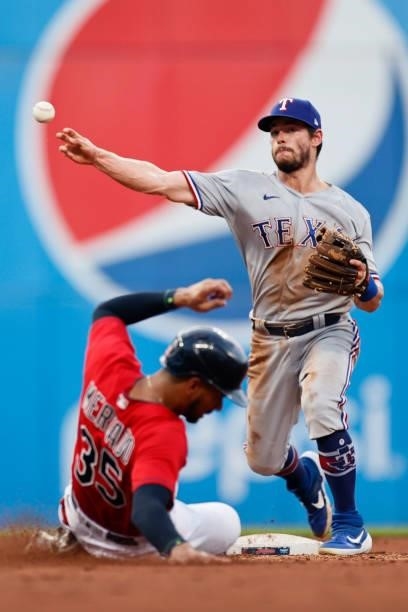 Nick Solak of the Texas Rangers throws over Oscar Mercado of the Cleveland Indians at second base to complete the double play on Yu Chang at first...