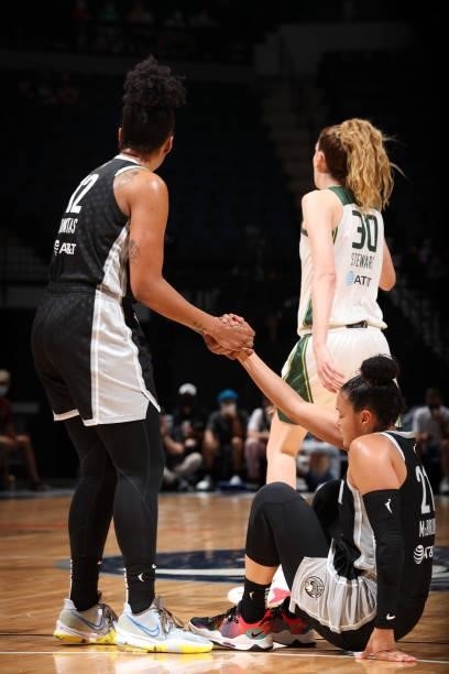 Damiris Dantas of the Minnesota Lynx helps up Kayla McBride during the game against the Seattle Storm on August 24, 2021 at Target Center in...