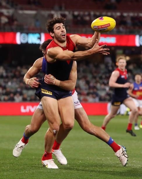 Christian Petracca of the Demons handpasses the ball Jarryd Lyons of the Lions during the 2021 AFL First Qualifying Final match between the Melbourne...