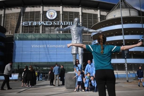 Fans pose with the newly-unveiled statue of former Manchester City footballer Vincent Kompany outside the stadium ahead of the English Premier League...
