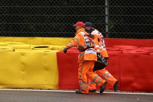 Race marshalls carry a piece of the car of McLaren's British driver Lando Norris after he crashed in the qualifying session of the Formula One...