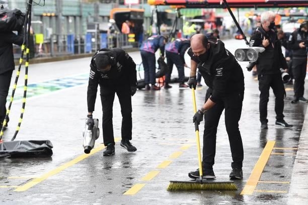 Staff members clear and dry rain water from the pit lane after the qualifying session of the Formula One Belgian Grand Prix at the Spa-Francorchamps...