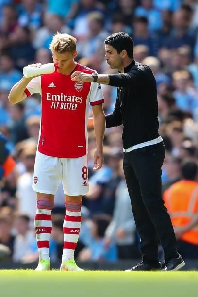 Martin Odegaard of Arsenal gets instructions from Mikel Arteta the head coach / manager of Arsenal during the Premier League match between Manchester...