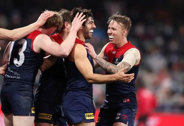 Christian Petracca of the Demons surrounded by Clayton Oliver and James Harmes after kicking a goal during the 2021 AFL First Qualifying Final match...
