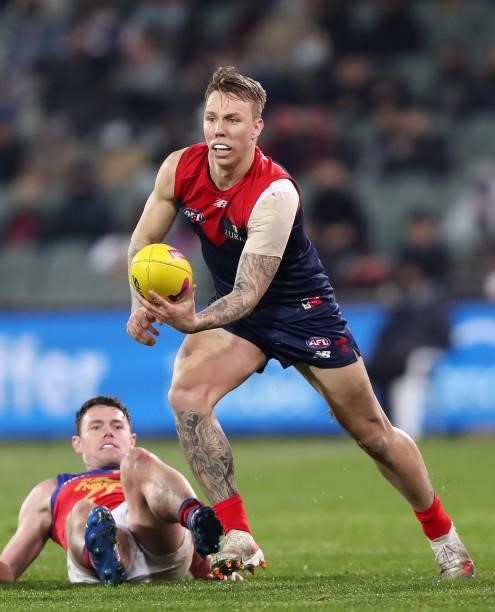 James Harmes of the Demons handpasses the ball with Lachie Neale of the Lions on the ground during the 2021 AFL First Qualifying Final match between...