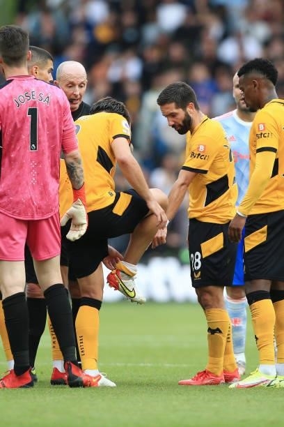 Referee Mike Dean looks on as Joao Moutinho of Wolverhampton Wanderers points towards the ankle of teammate Ruben Neves of Wolverhampton Wanderers...