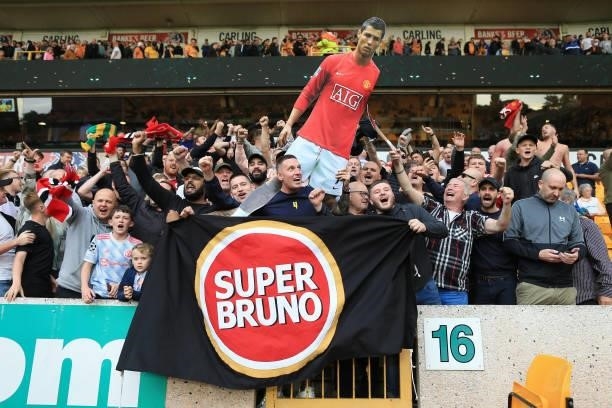 Manchester United fans hold up a cardboard cut-out of Cristiano Ronaldo alongside a banner in support of 'Super' Bruno Fernandes during the Premier...