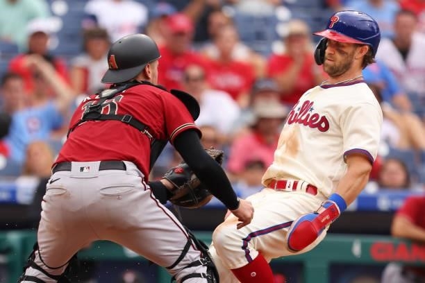 Catcher Carson Kelly of the Arizona Diamondbacks tags out Bryce Harper of the Philadelphia Phillies attempting to score on a ball hit by Andrew...
